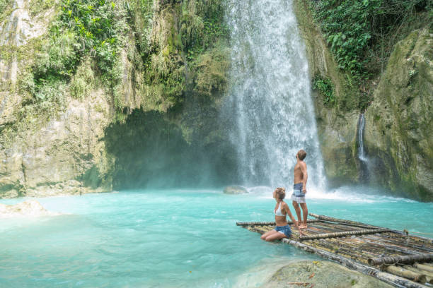 istock Young couple contemplating beautiful tropical waterfall 1124572800