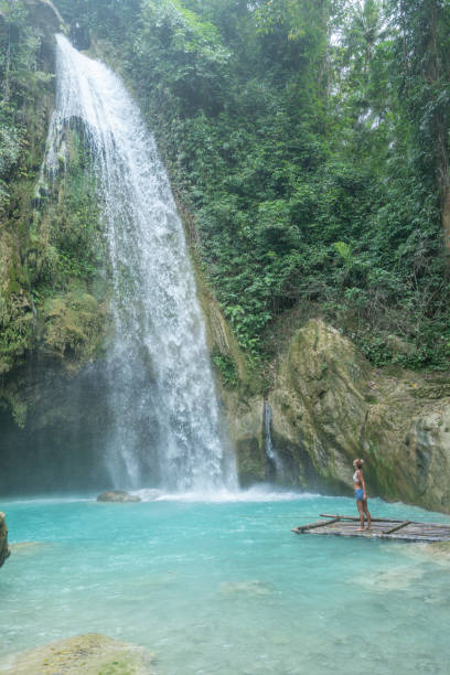 istock Young woman admiring beautiful waterfall in tropical rainforest 1124573034