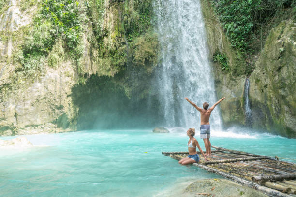 istock Young couple contemplating beautiful tropical waterfall 1124574686