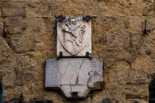 A commemorative stone with on top a rampant lion in San Gimignano, Tuscany, Italy. The wrinting is dated back to middle-age