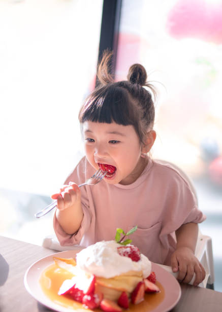 카페에서 핫 케이크를 먹는 어린 소녀 - dessert food sweet food strawberry 뉴스 사진 이미지