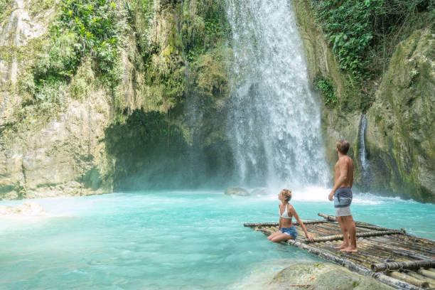 istock Young couple contemplating beautiful tropical waterfall 1124582860