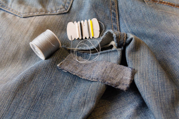 Sewing needles and thread, embroidered on the äæèíñîâûõ pants. Repair of defects Sewing needles and thread, embroidered on the джинсовых pants. Repair of defects hole in pants stock pictures, royalty-free photos & images