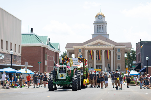 Jasper, Indiana, USA - August 5, 2018: The Strassenfest Parade, Man driving an old tractor, pulling a trailer with people