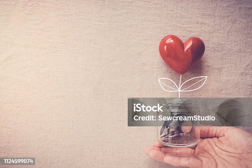 istock Hand holding a jar of heart tree growing on money coins, social responsibility and donation concept 1124599074