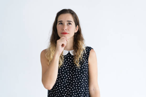 istock Pensive young woman touching chin and looking up 1124605245