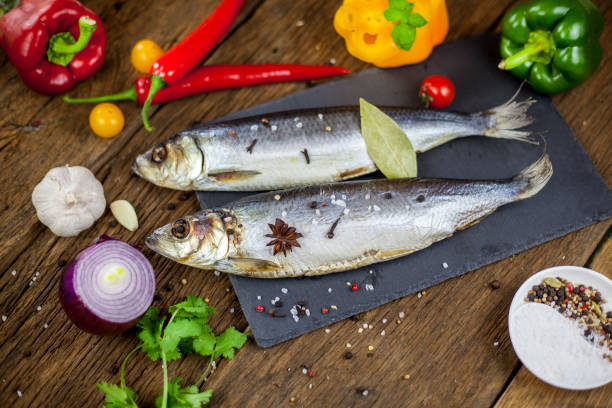 istock Dry fish herring on a wooden background with vegetables and specials 1124619656