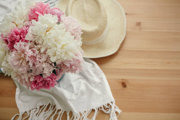 istock Beautiful peonies in vase and straw hat on rustic wooden table top view with space for text. Hello summer. Happy mothers day greeting card. International Women's Day. Valentines day. 1124633336