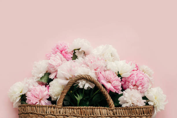 istock Hello spring concept. Stylish straw rustic bag with white and pink peonies on pastel pink paper, flat lay with copy space. International Women's Day. Happy mothers day, floral greeting card 1124634483
