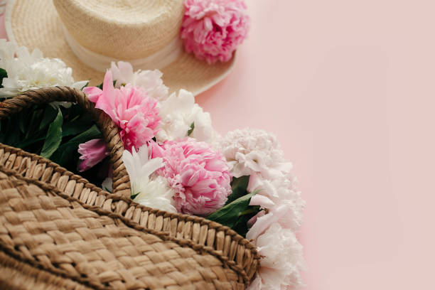 istock Straw hat and rustic bag with white and pink peonies on pastel pink paper.  Hello spring image with copy space. Summer vacation concept. International Women's Day. Happy mothers day 1124634519