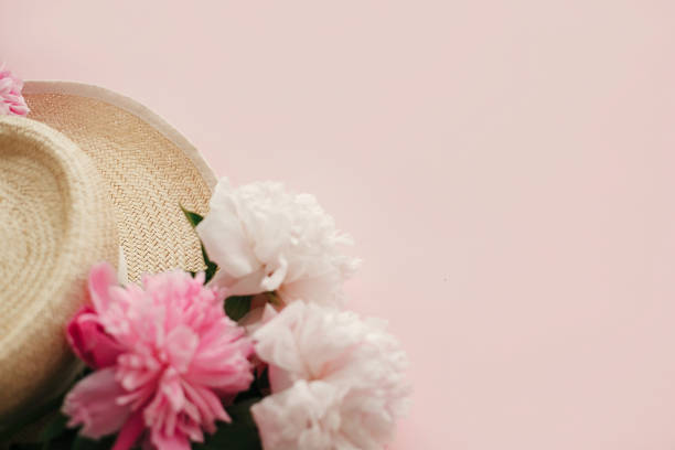istock Straw hat with white and pink peonies on pastel pink paper, flat lay.  Hello spring image with copy space. Summer vacation concept. International Women's Day. Happy mothers day 1124634574