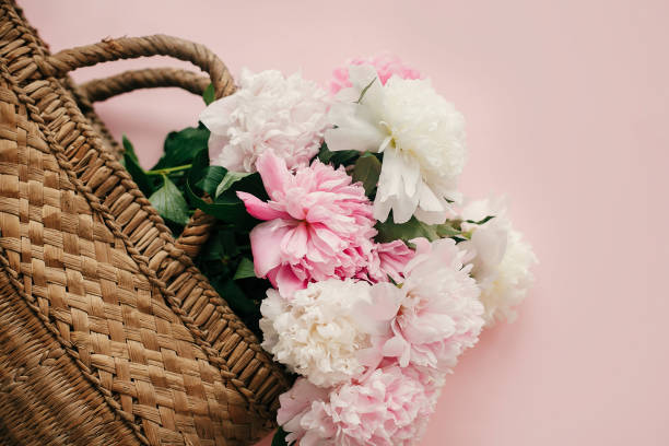 istock Stylish straw rustic bag with white and pink peonies on pastel pink paper, flat lay with copy space. Hello spring concept. International Women's Day. Happy mothers day, floral greeting card 1124635321