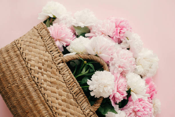 istock Hello spring concept. Stylish straw rustic bag with white and pink peonies on pastel pink paper, flat lay with copy space. International Women's Day. Happy mothers day, floral greeting card 1124635406