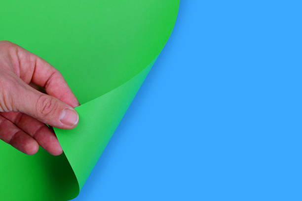 istock Hand turning empty page of green paper. 1124635930