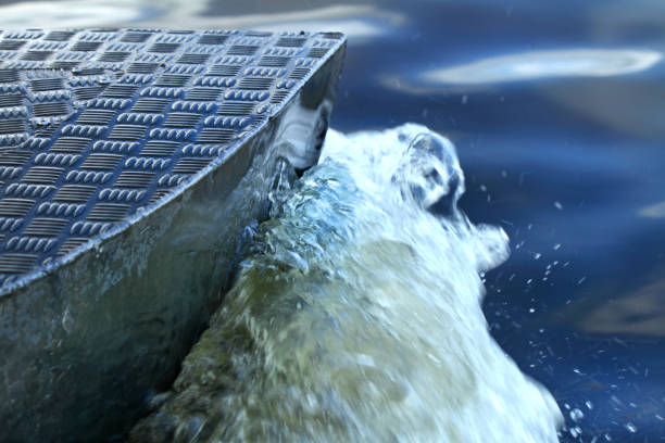 A closeup shot of a boat's metal pontoon cutting through the water creating a wake as it propels its self forward