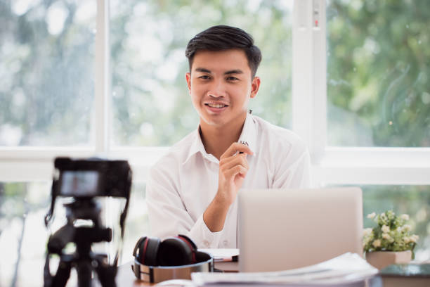 Happy Asian businessman videoblog / blogger vlogger recording online course or tutorial strategy presentation pass video for teaching live marketing sharing social media channel by mirrorless camera