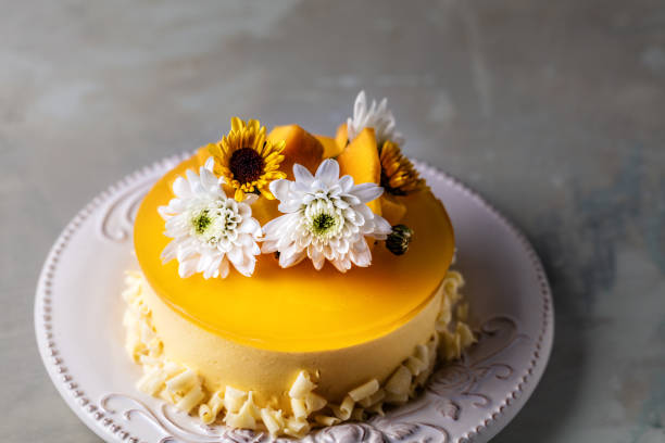 istock Glazed Mango cheesecake with flowers and fresh mango pieces on round plate on grey background 1124642496