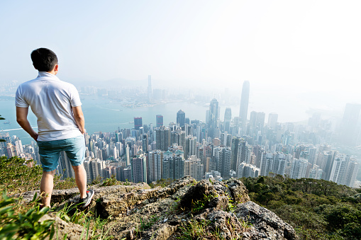 Men standing on the top of mountain and looking cityscape.