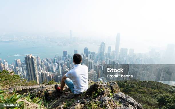 Mężczyźni Siedzący Na Szczycie Góry I Wyglądający Pejzaż Miejski - zdjęcia stockowe i więcej obrazów Miasto