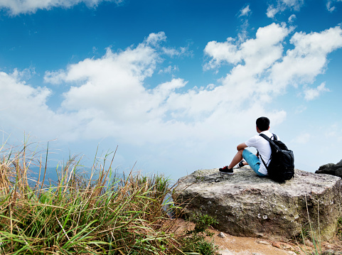 Man backpacker sitting on the top of mountain.