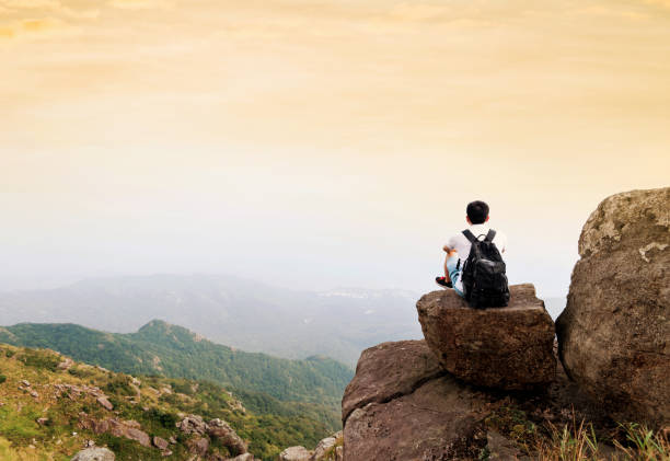 istock Man backpacker sitting on the top of mountain at sunset 1124646264
