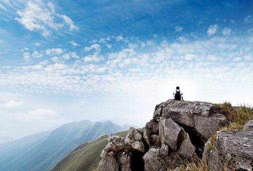 Man backpacker sitting on the top of mountain.