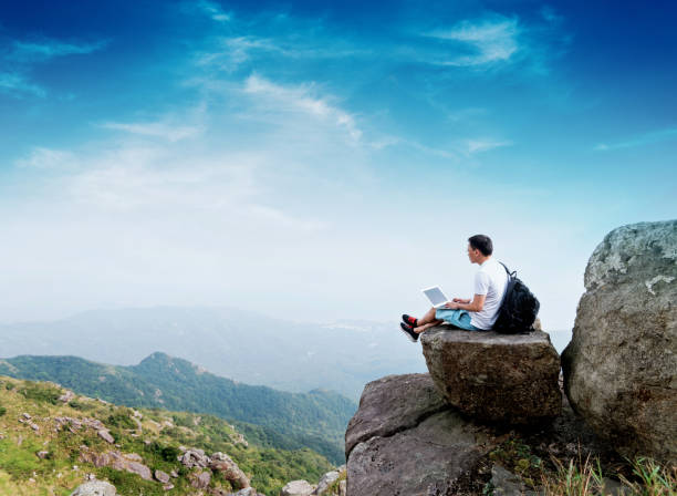 istock Man using laptop on top of mountain 1124646324