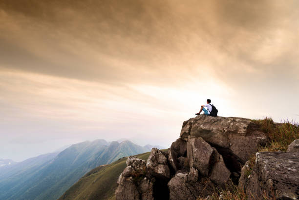 istock Man backpacker sitting on the top of mountain at sunset 1124646389