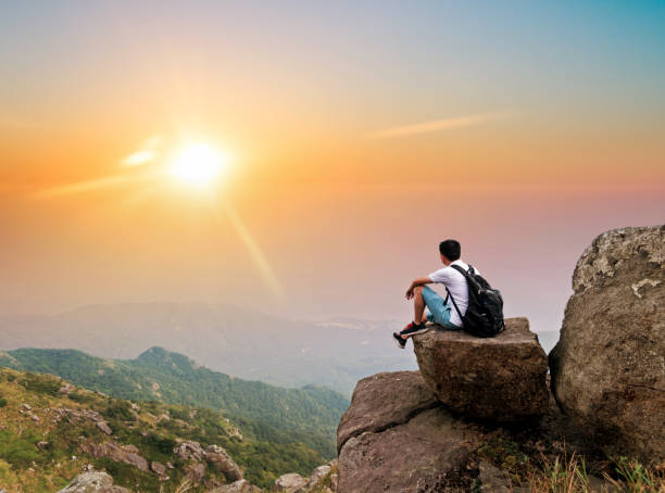 istock Man backpacker sitting on the top of mountain at sunset 1124646390