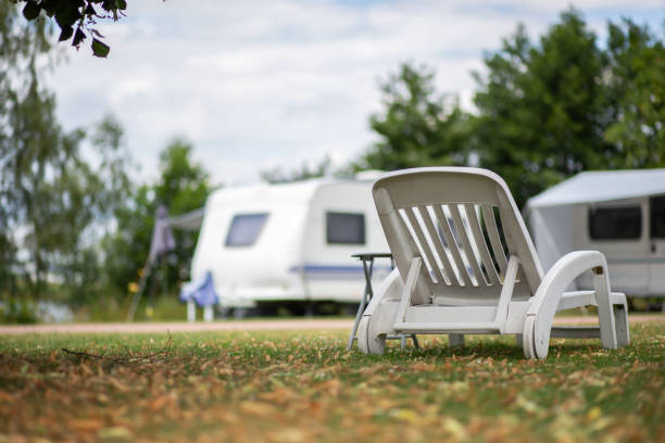 weißer liegestuhl auf einer wiese auf einem campingplatz - campingplatz stock-fotos und bilder