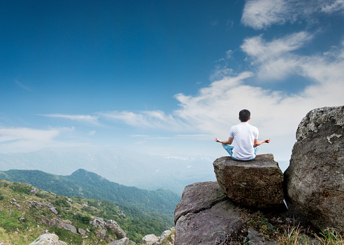Man doing yoga on top of mountain.