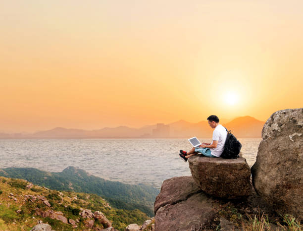 istock Man using laptop on top of the cliff 1124647856