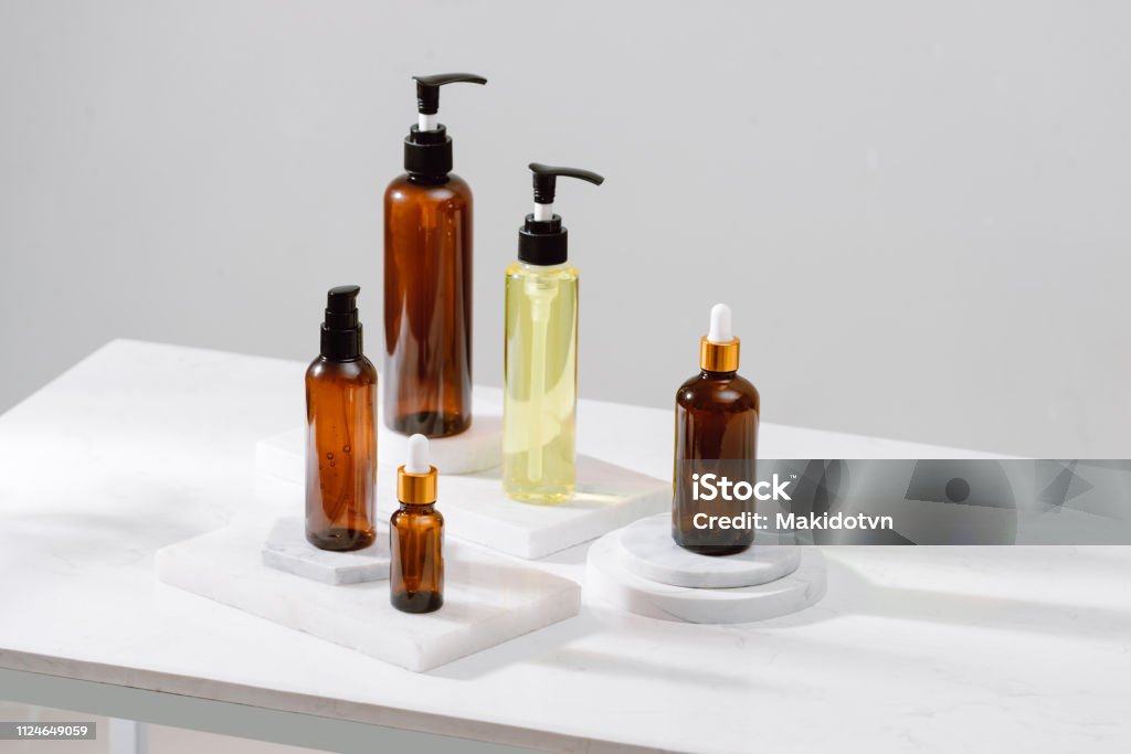 Spa cosmetics in brown glass bottles on gray concrete table. Copy space for text. Beauty blogger, salon therapy, branding mockup, minimalism concept Merchandise Stock Photo