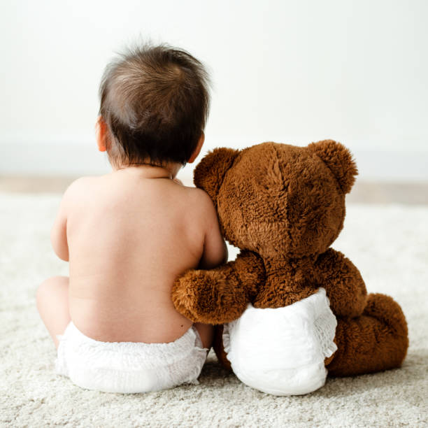 la schiena di un bambino con un orsacchiotto - teddy bear baby toy stuffed animal foto e immagini stock