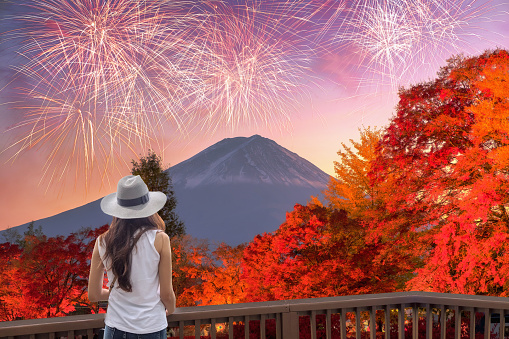 Young asian woman sightseeing Fuji-san with fireworks celebration in autumn season on wood terraced