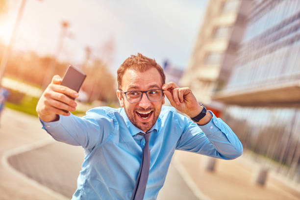 istock Funny businessman with thumbs up while using smartphone outdoors. 1124657325