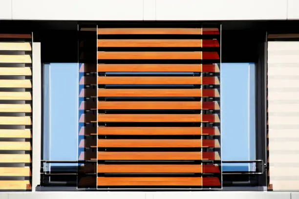 Photo of Computer graphic image of jalousie / louvers / blinds fragments in yellow and orange colors. Lath structures. Abstract modern architecture, interior or technology background image.