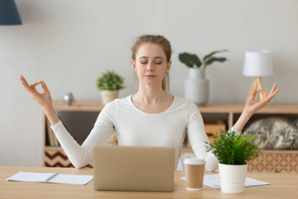 istock Young woman student taking break meditating at home office desk 1124667499