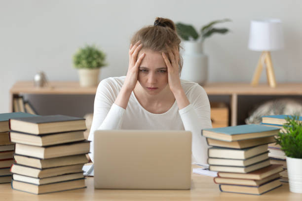 istock Stressed college student tired of hard learning with books laptop 1124667608
