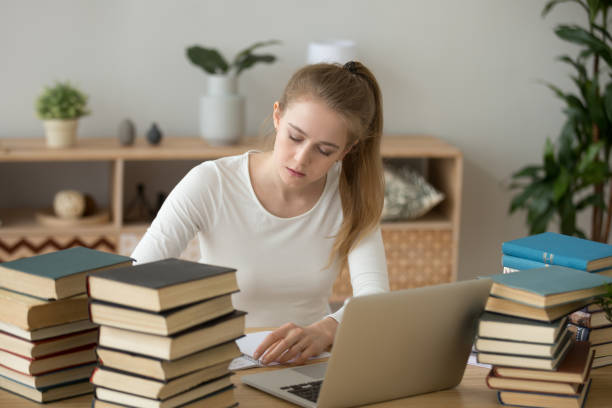 Teen girl preparing for exam writing essay coursework in notebook