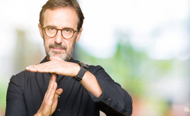 istock Middle age priest man wearing catholic robe Doing time out gesture with hands, frustrated and serious face 1124669321