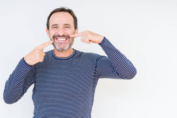 istock Handsome senior man over isolated background smiling confident showing and pointing with fingers teeth and mouth. Health concept. 1124670545