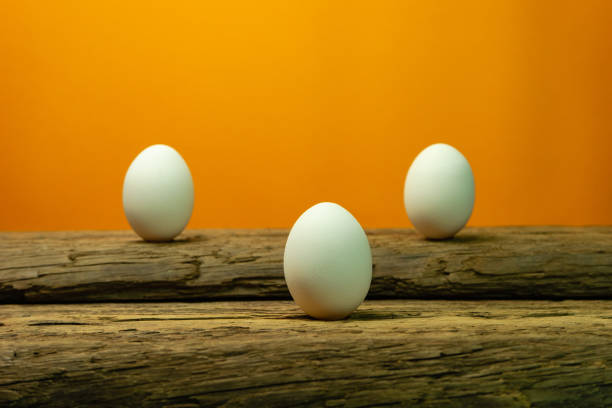 istock Three Eggs on a old oak wooden table orange background. 1124672817
