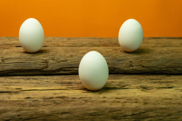 istock Three Eggs on a old oak wooden table orange background. 1124675017