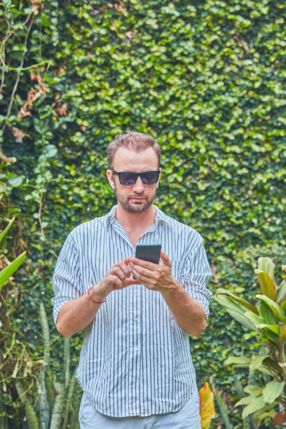 istock Man with sunglasses and summer shirt using smartphone. 1124681184