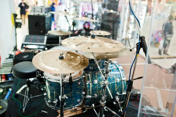 Photo of Drum set on stage in a concert hall behing glass wall.
