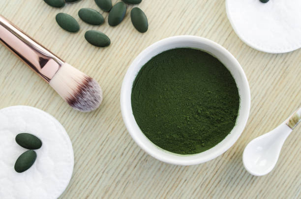 spirulina em pó na tigela branca pequena. ingrediente de máscara de rosto caseiro. superalimento e tratamento de beleza natural. close-up, vista, cópia espaço superior. - face powder fotos - fotografias e filmes do acervo