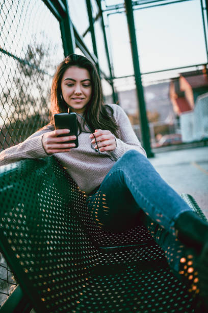 istock Cute Female Typing On a Smartphone While Lying On a Playground Bench 1124687090