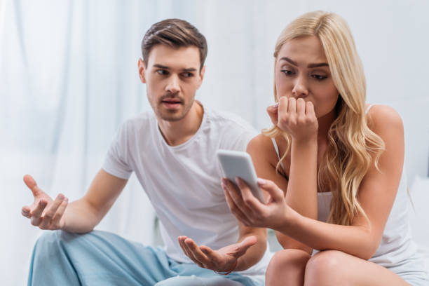 istock emotional man talking and looking at young wife using smartphone in bedroom, mistrust concept 1124687184