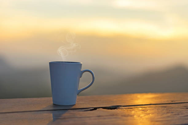 日光を浴びて山々の風景の上に屋外の木製のテーブルの上に蒸気とカップコーヒーと紅茶。美しさの自然の背景。ライフスタイルコンセプト - steam coffee cup black coffee non alcoholic beverage ストックフォトと画像